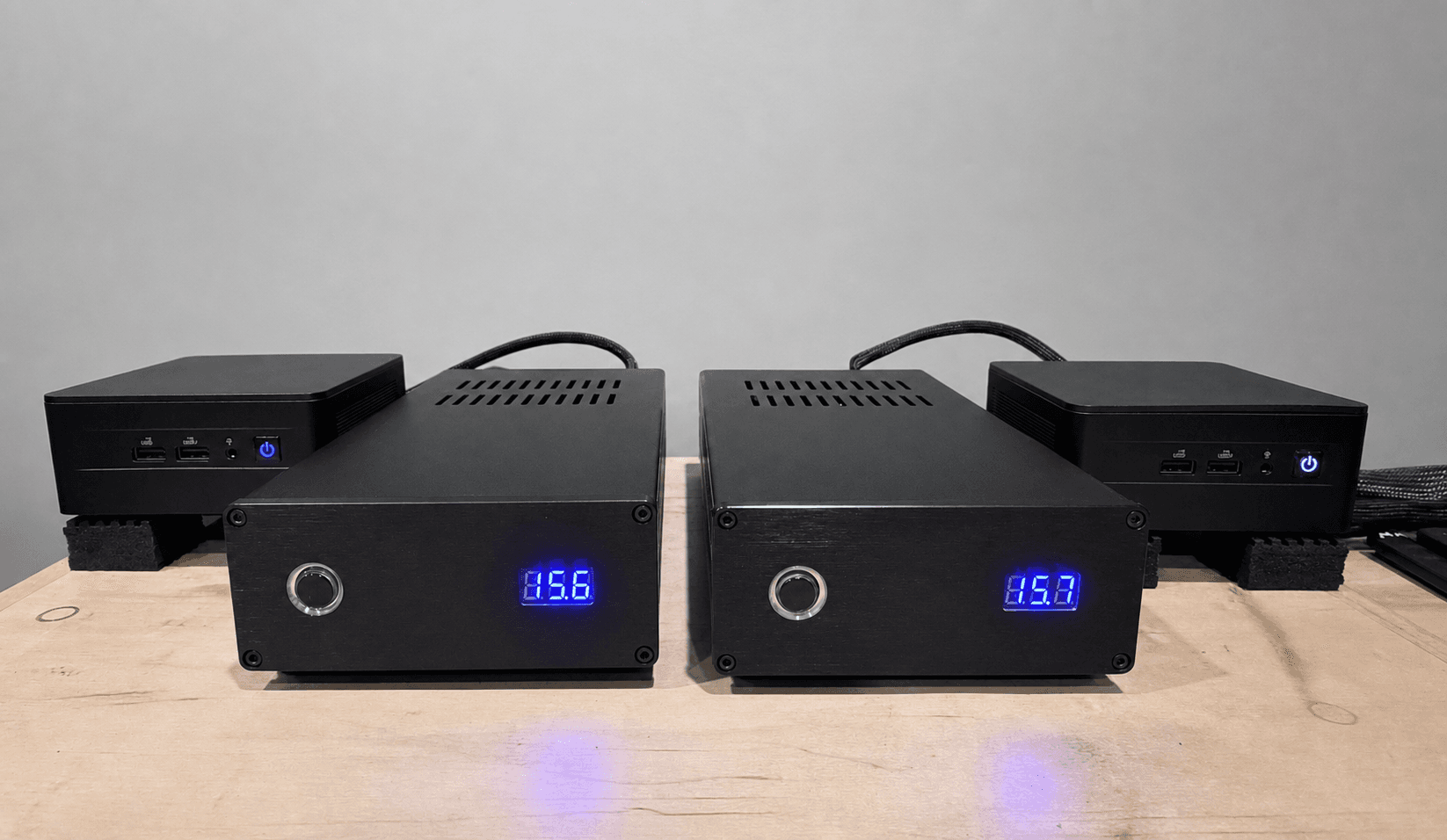 Two DeJitter It NUC-X units with their matching linear power supplies on a wood platform.